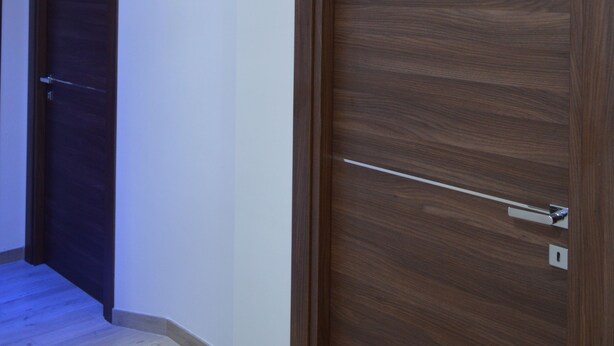 A hallway with wooden doors and a light fixture on the ceiling.