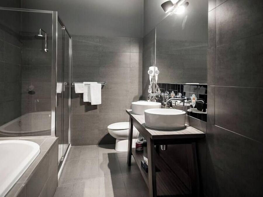 A modern bathroom with a glass-enclosed shower, a freestanding bathtub, a vanity with two sinks, and a toilet.