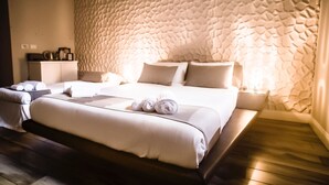A hotel room with a textured wall, a bed with white linens, a bedside table with a lamp, and a wooden floor. - Domus Tacito Luxury (Rome)