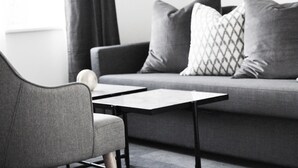 Una sala moderna con un sofá gris, dos sillones a juego y una mesita.
