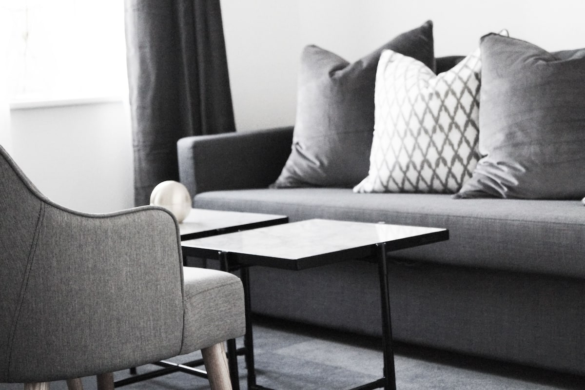 A modern living room with a grey sofa, two matching armchairs, and a small table.
