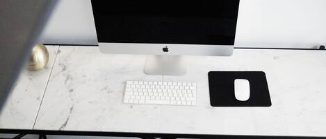 Escritorio con monitor, teclado y ratón sobre una mesa de mármol.