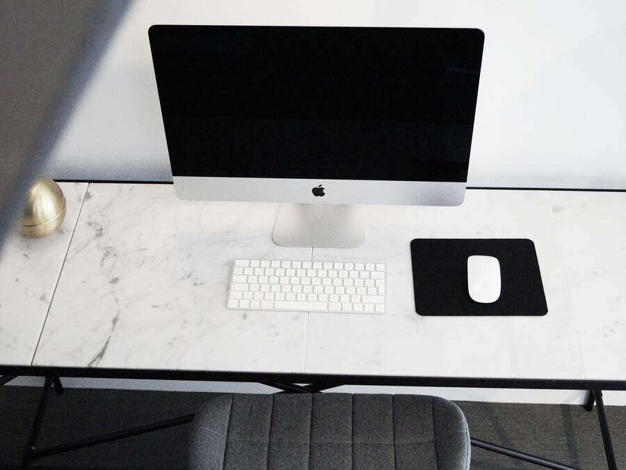 A desktop with a monitor, keyboard, and mouse on a marble table.