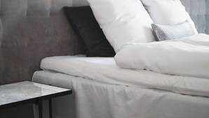 Una cama bien hecha con ropa blanca y un cabecero tapizado en gris.