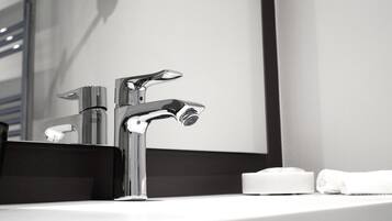 A modern bathroom with a chrome faucet, a mirror, and a white towel on the sink.