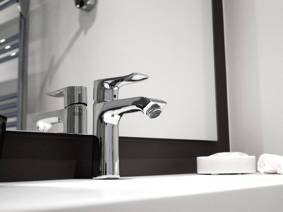 Une salle de bain moderne avec un robinet chromé, un miroir et une serviette blanche posée sur le lavabo.