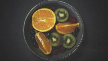 Un tazón con rodajas de naranja, kiwi y bayas.