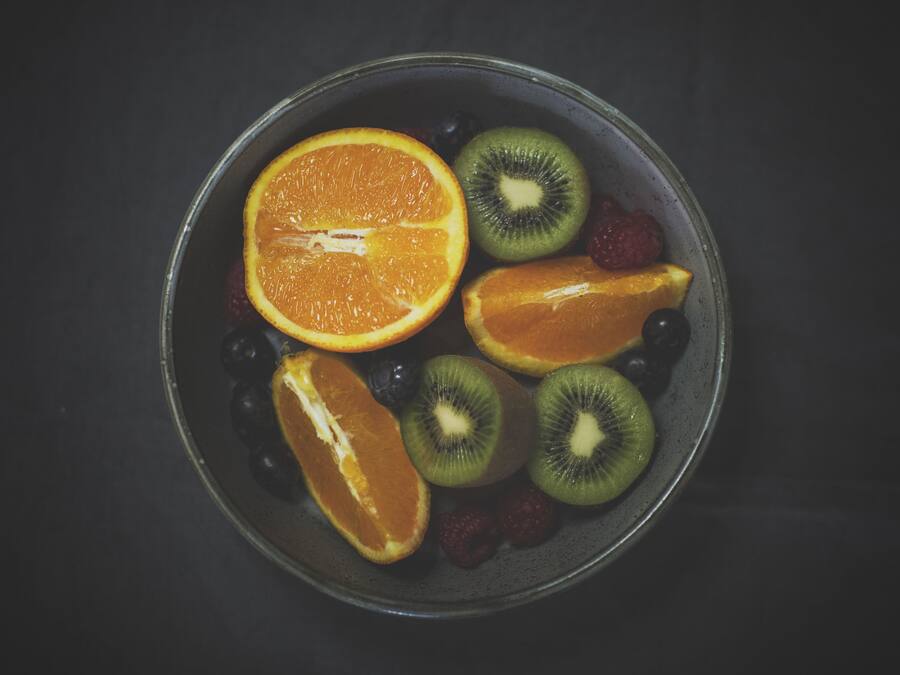 Un tazón con rodajas de naranja, kiwi y bayas.