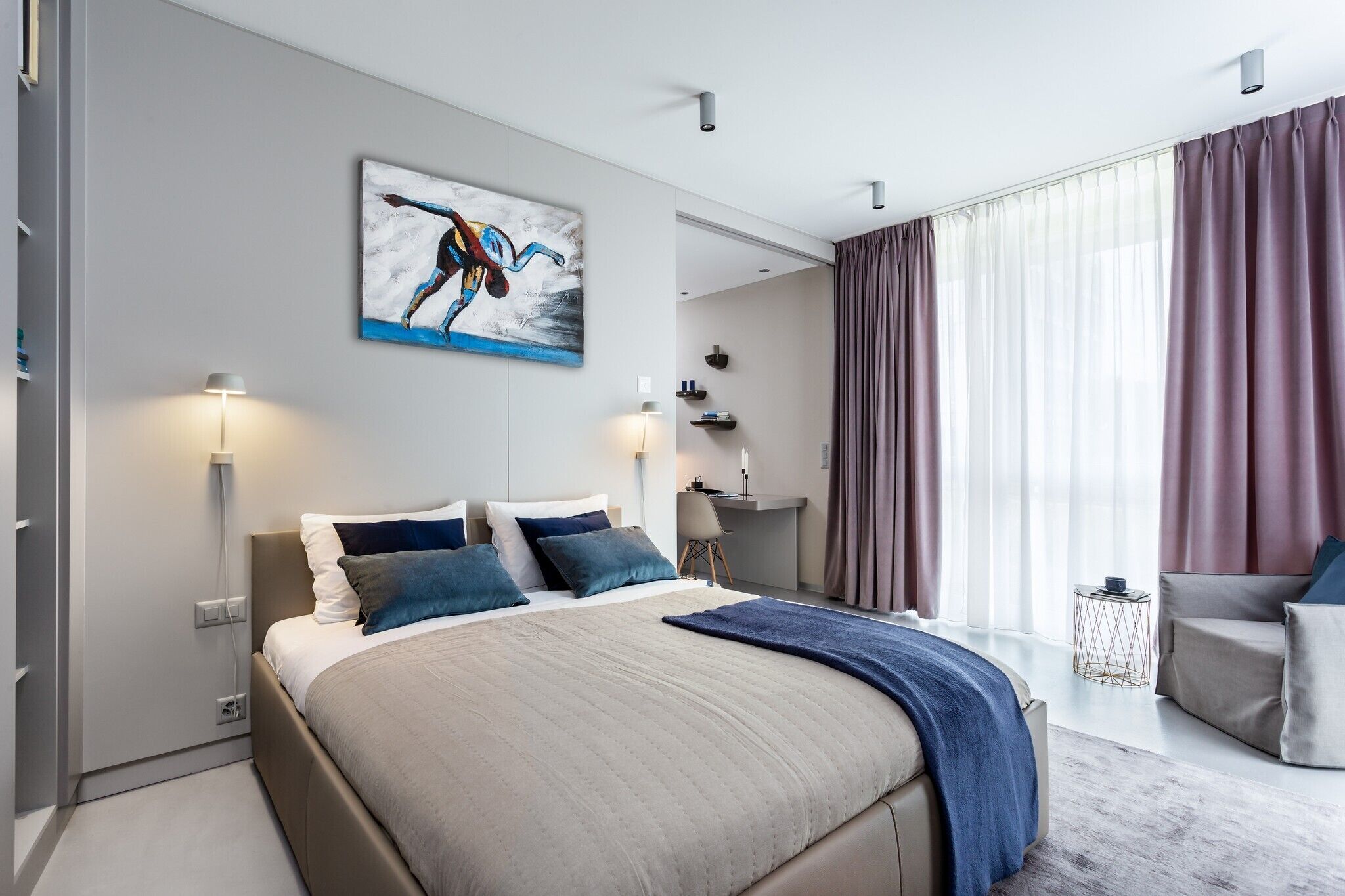 Une chambre moderne avec un grand lit, un bureau et une vue sur l’extérieur.