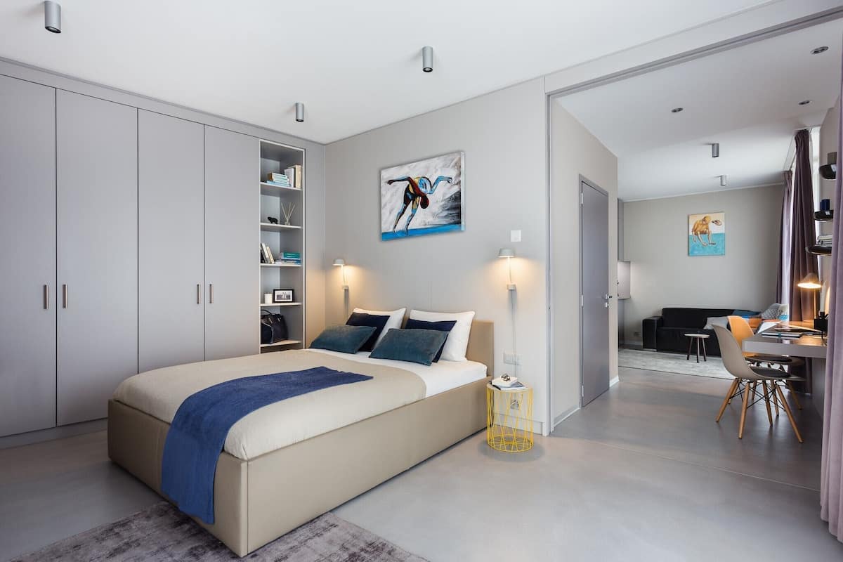 A modern bedroom with a large bed, bedside tables, a desk, and a chair.