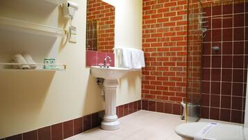 A bathroom with a white pedestal sink, a mirror, a white toilet, and a glass-enclosed shower.