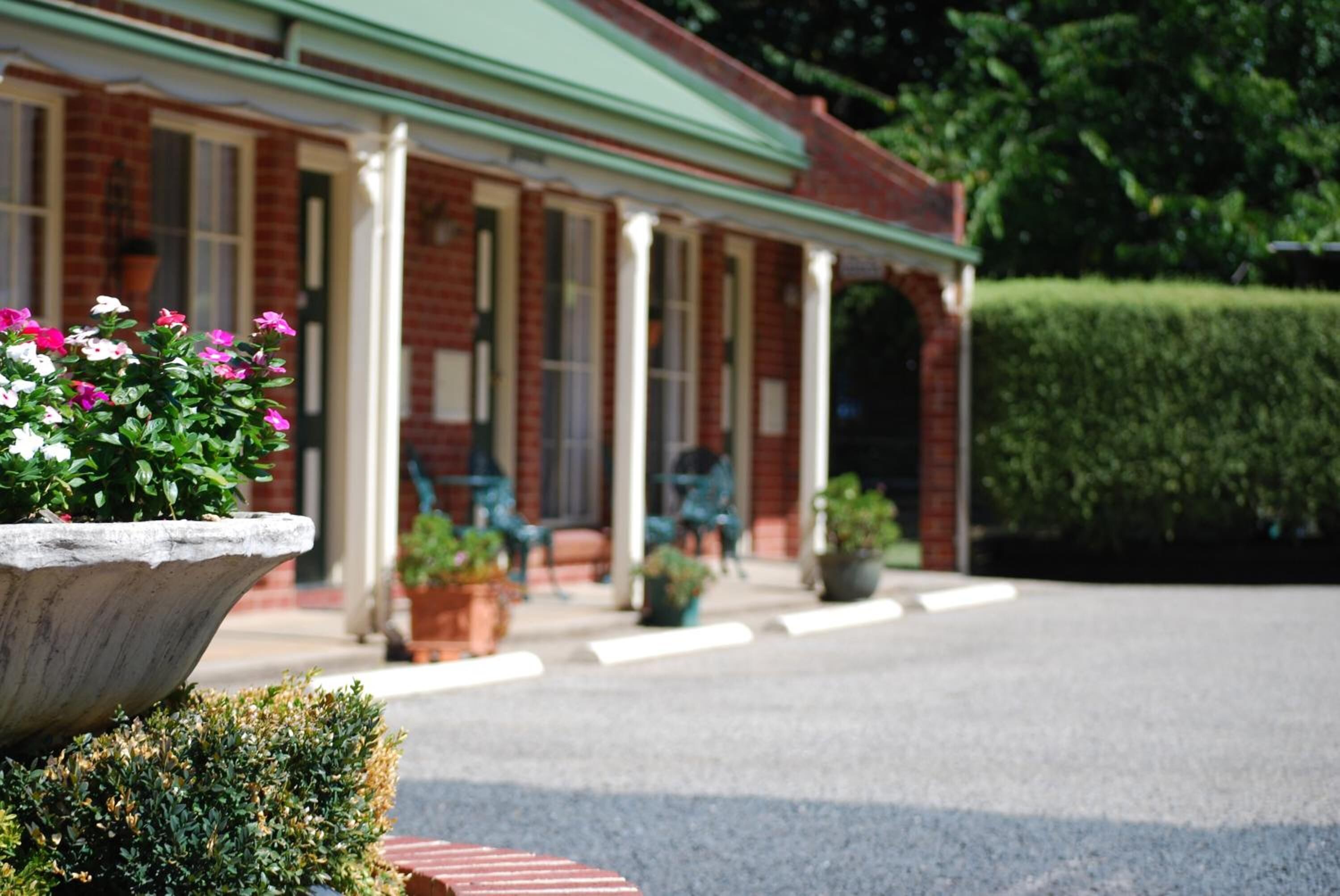 A brick building with a green awning, a covered porch, and potted plants.