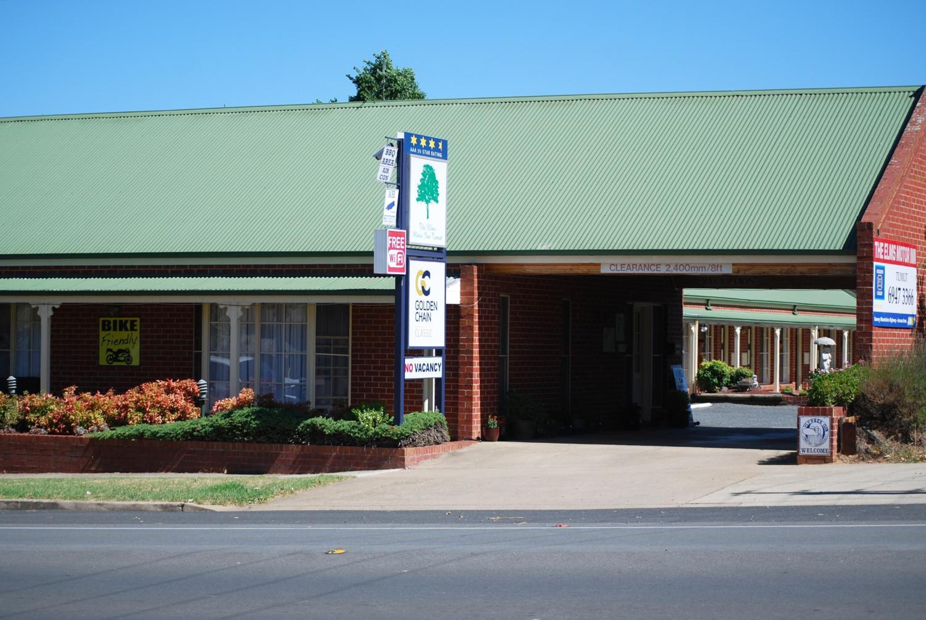 A building with a green roof, a 'Bike Friendly' sign, a 'No Vacancy' sign, and a 'Clearance 2.400mm/8ft' sign.