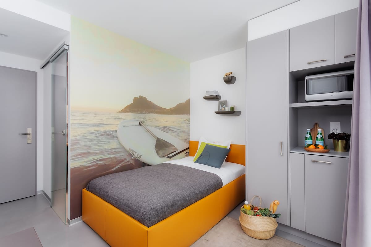 A bedroom with a bed, a wardrobe, a microwave, and a wall mural.