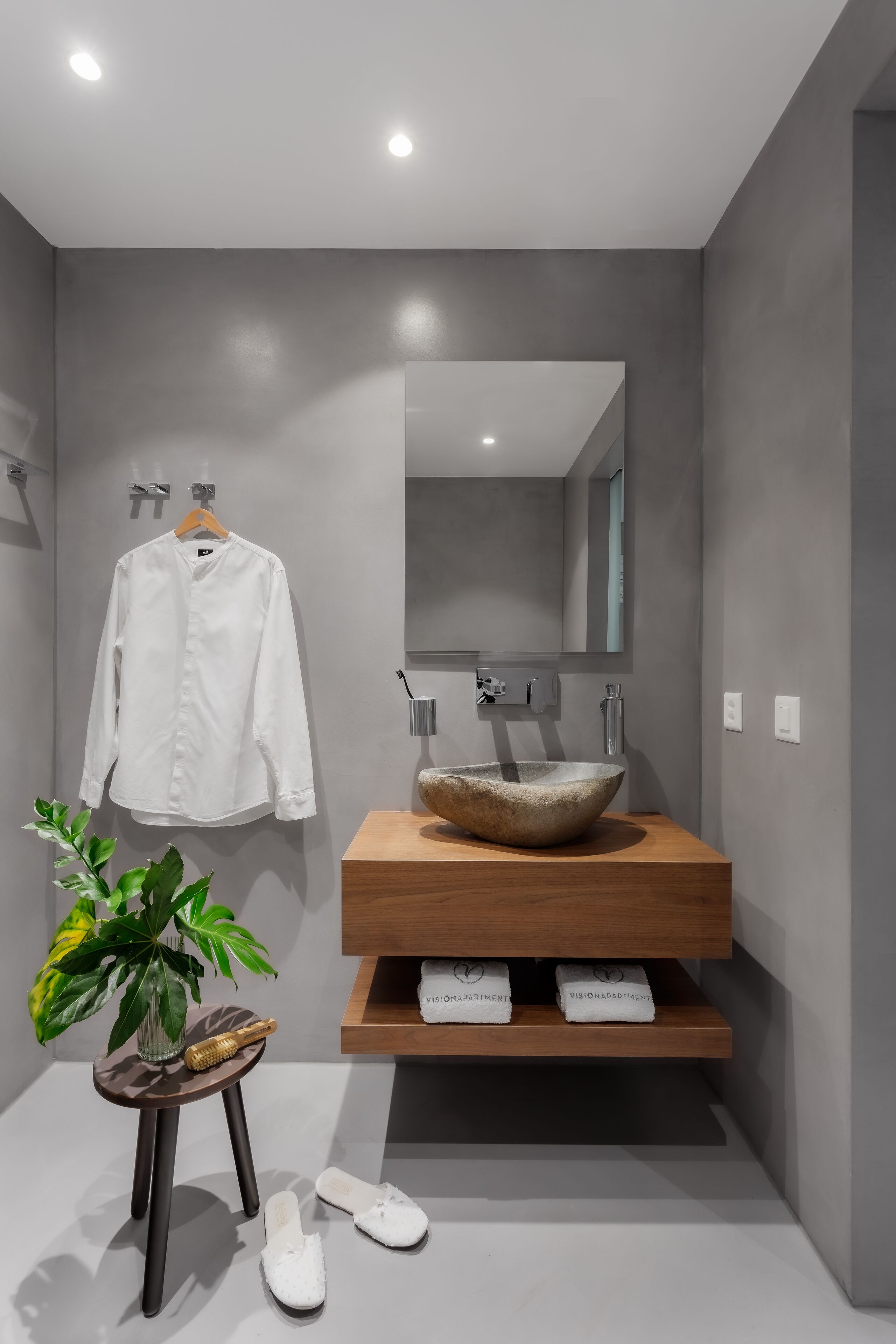 A modern bathroom with a large mirror, a wooden vanity, and a white sink.