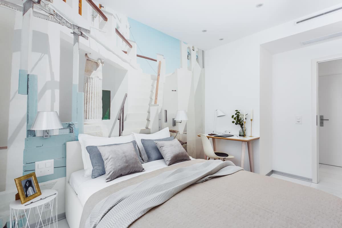 A modern bedroom with a large bed, a desk, and a chair.
