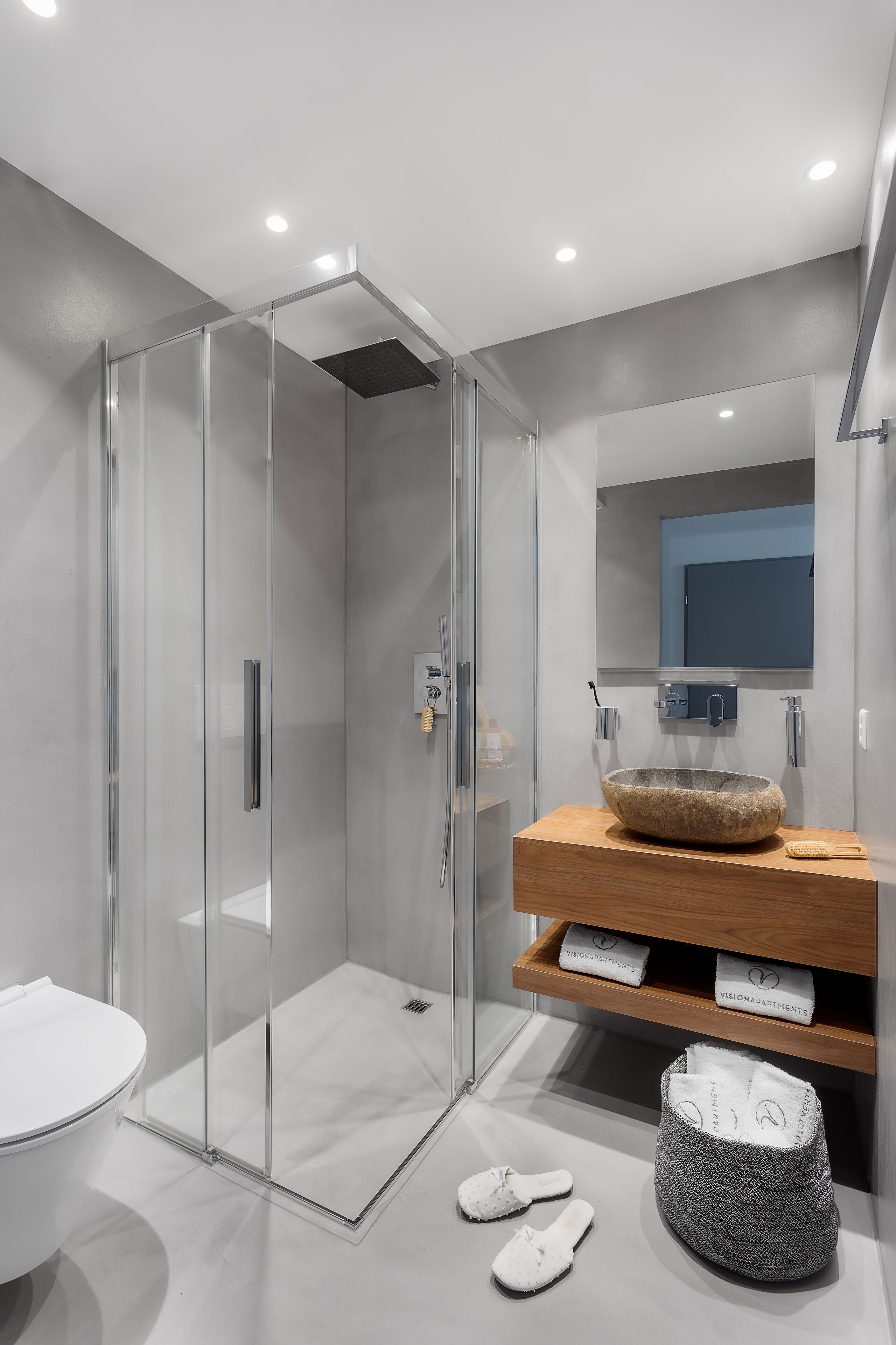 A modern bathroom with a glass-enclosed shower, a wooden vanity, and a large mirror.