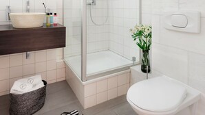 A modern bathroom with a glass-enclosed shower, a white sink, and a toilet.