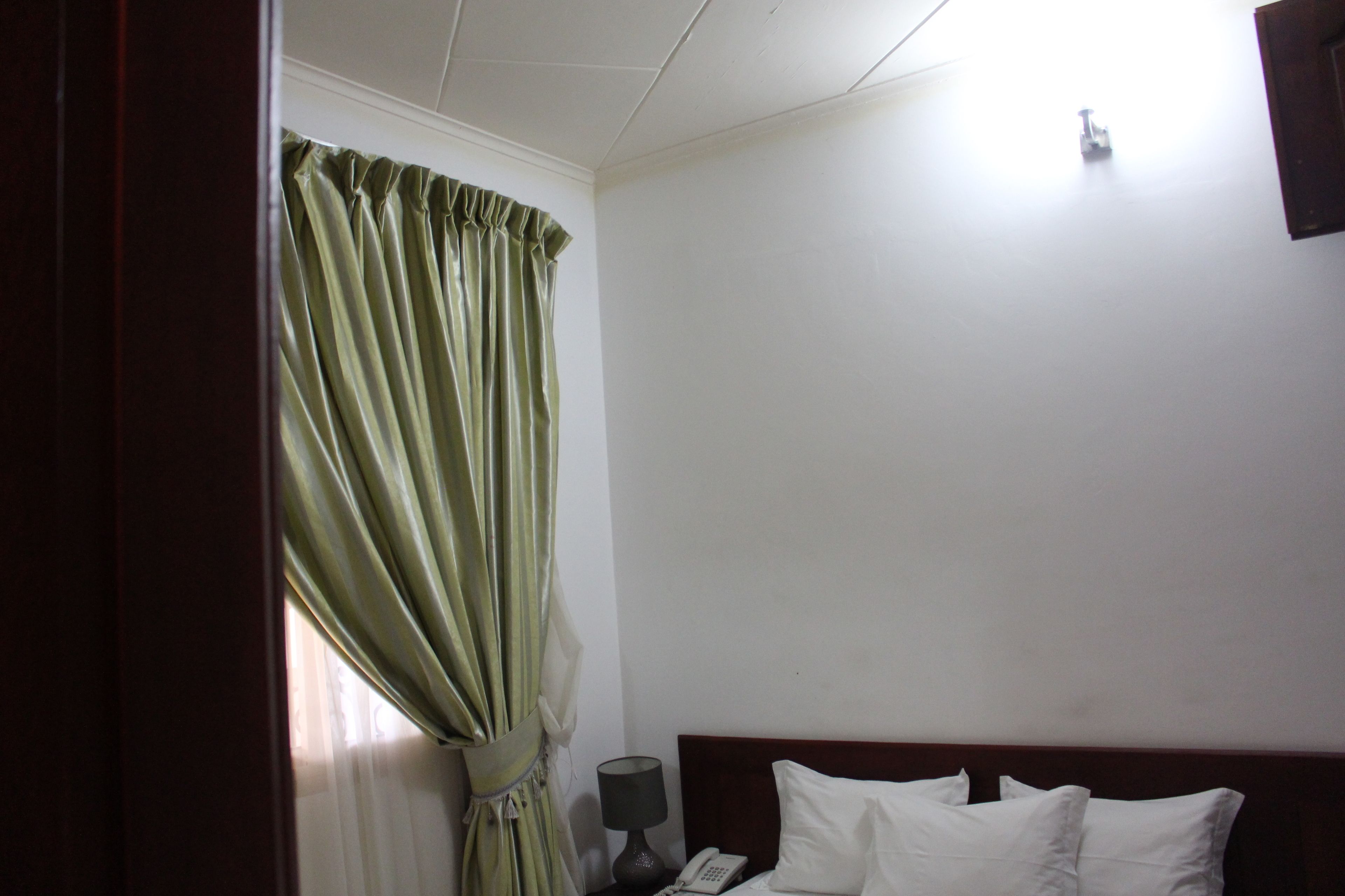 Une chambre d’hôtel avec un lit, une table de chevet, une lampe et un téléphone.