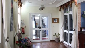 Un pasillo con piso pulido, una puerta con paneles de vidrio, una escalera y una planta en maceta.