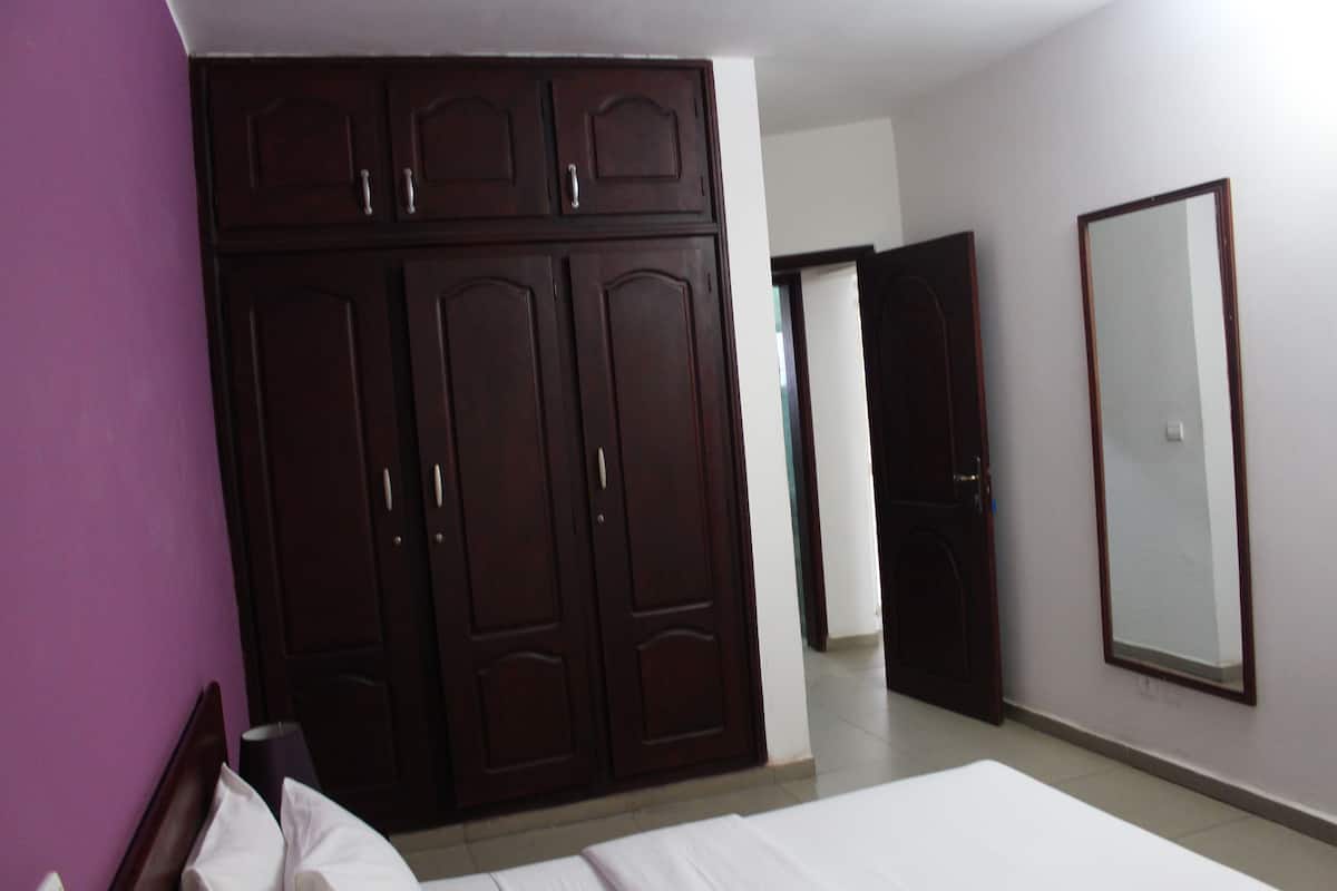 A bedroom with a large wardrobe, a bed, and a mirror on the wall.
