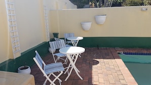 A patio area with a pool, white folding chairs, and a small table. - Daisy Lodge (Durban)