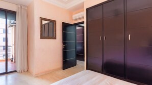 A bedroom with a bed, a wardrobe, a mirror, and an open door leading to a balcony.