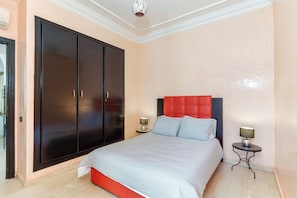 Una camera da letto con un letto grande, un armadio, due comodini e una parete decorata in rosso.