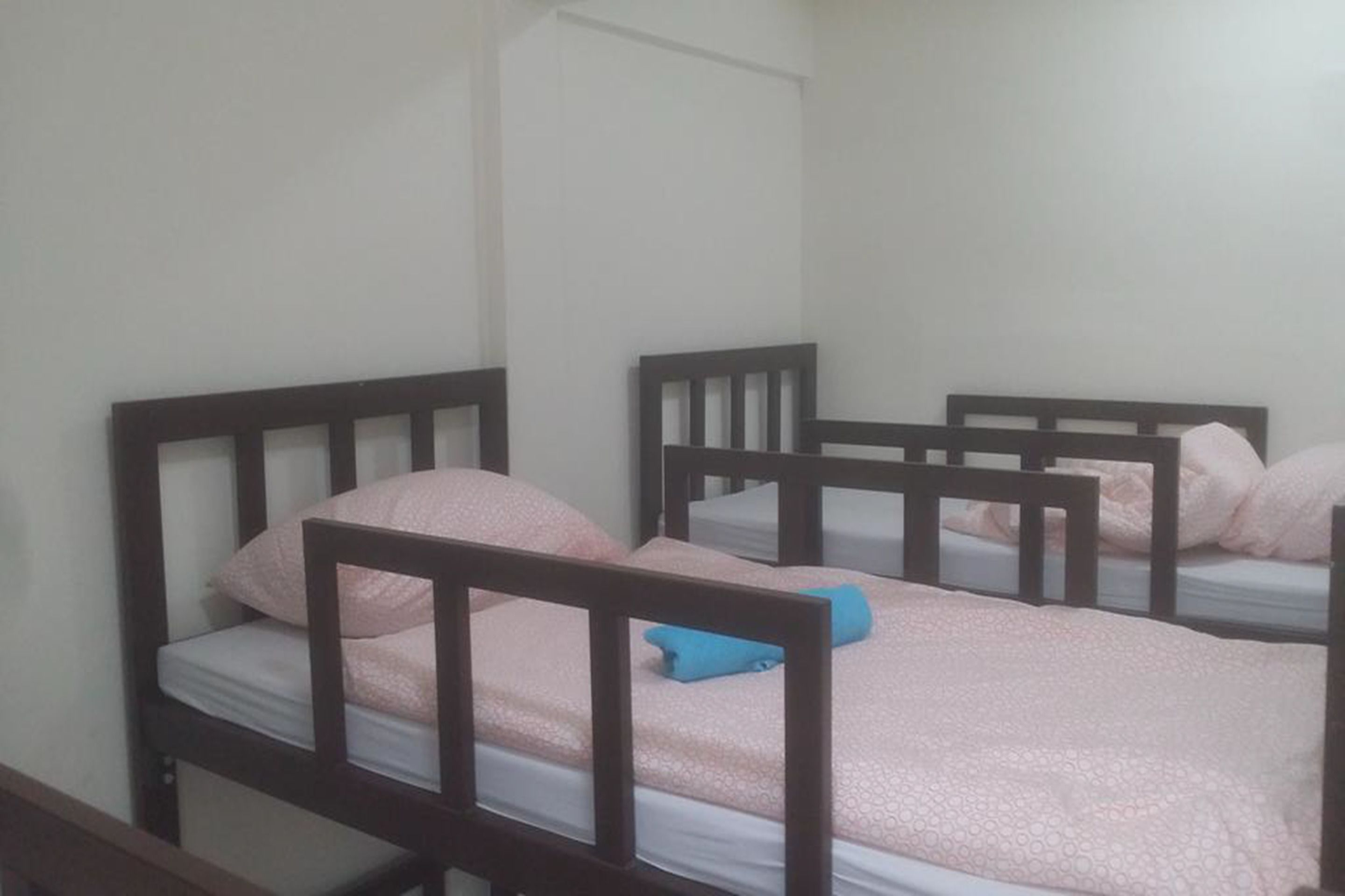 A room with four bunk beds, each with a wooden frame and pink bedding.