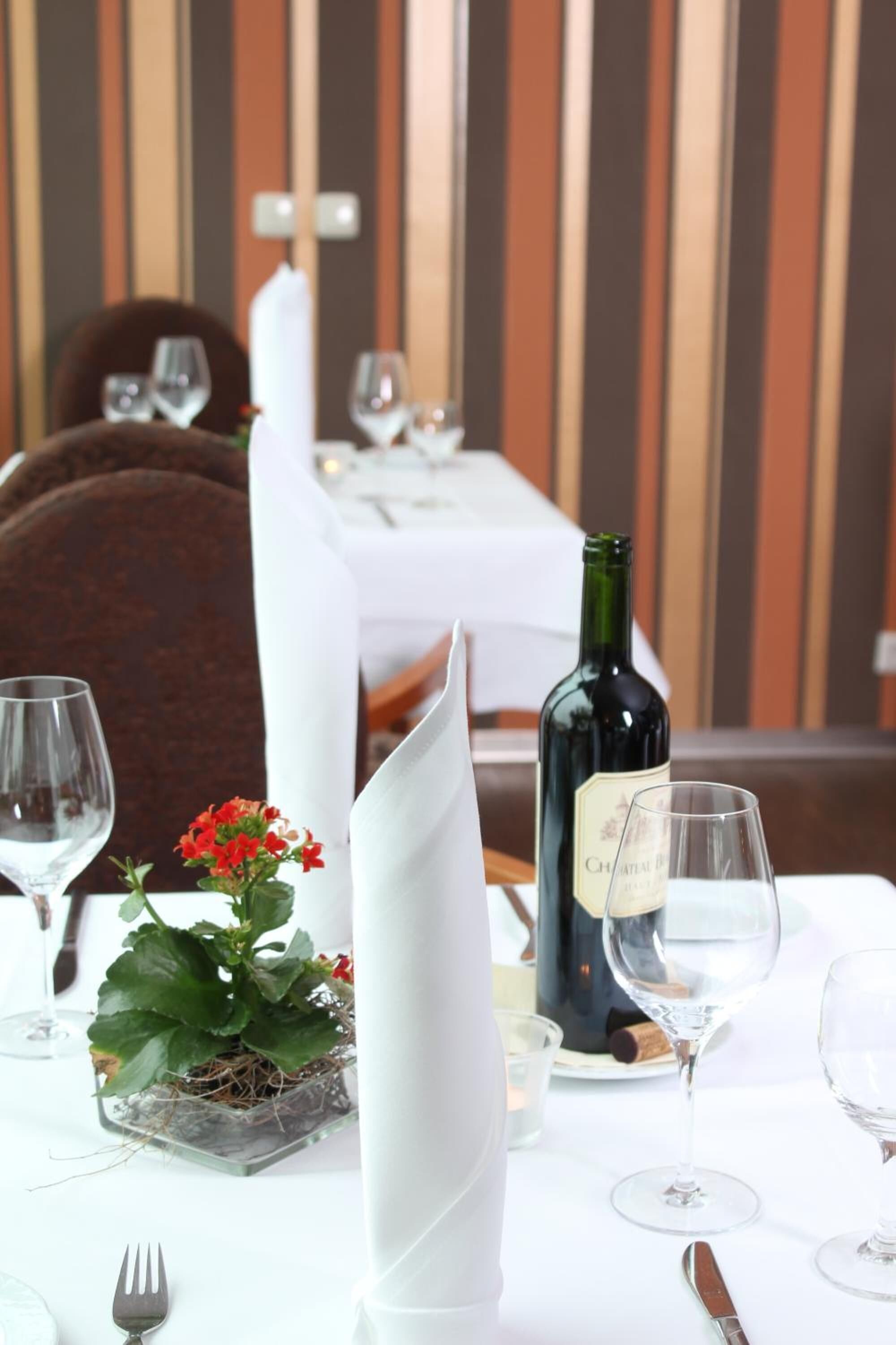 A dining table set with wine glasses, a bottle of wine, and a floral centerpiece.