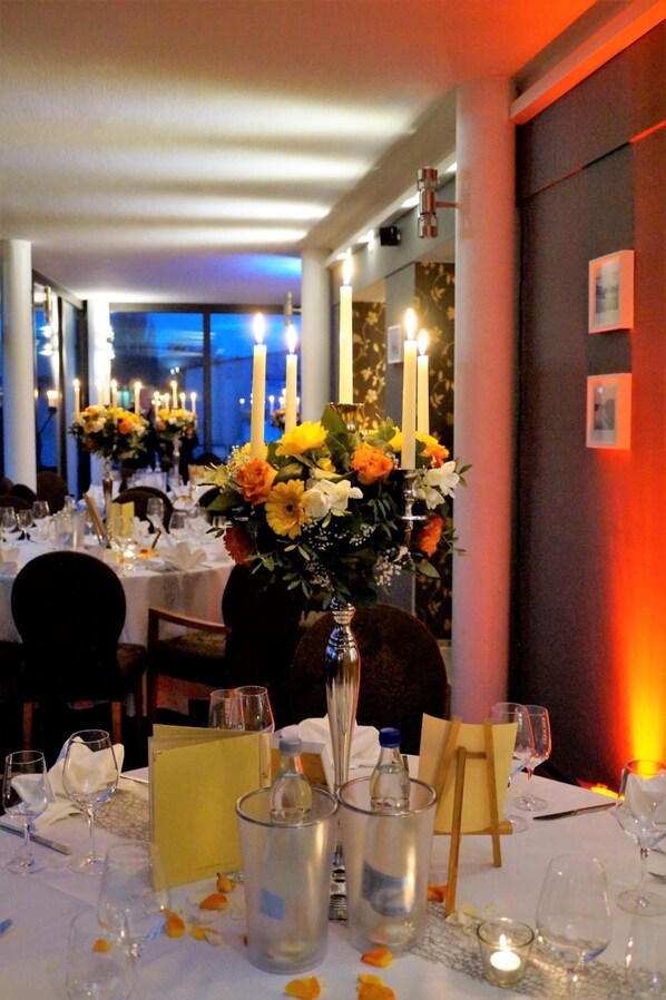 A dining area with tables set for a meal, candles, and floral centerpieces.