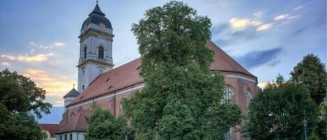 Una iglesia con una torre destacada y un árbol grande en primer plano.