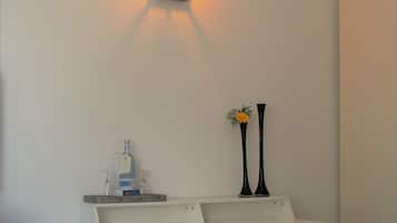 A desk with a white surface, two black vases, a bottle, and a small plant.