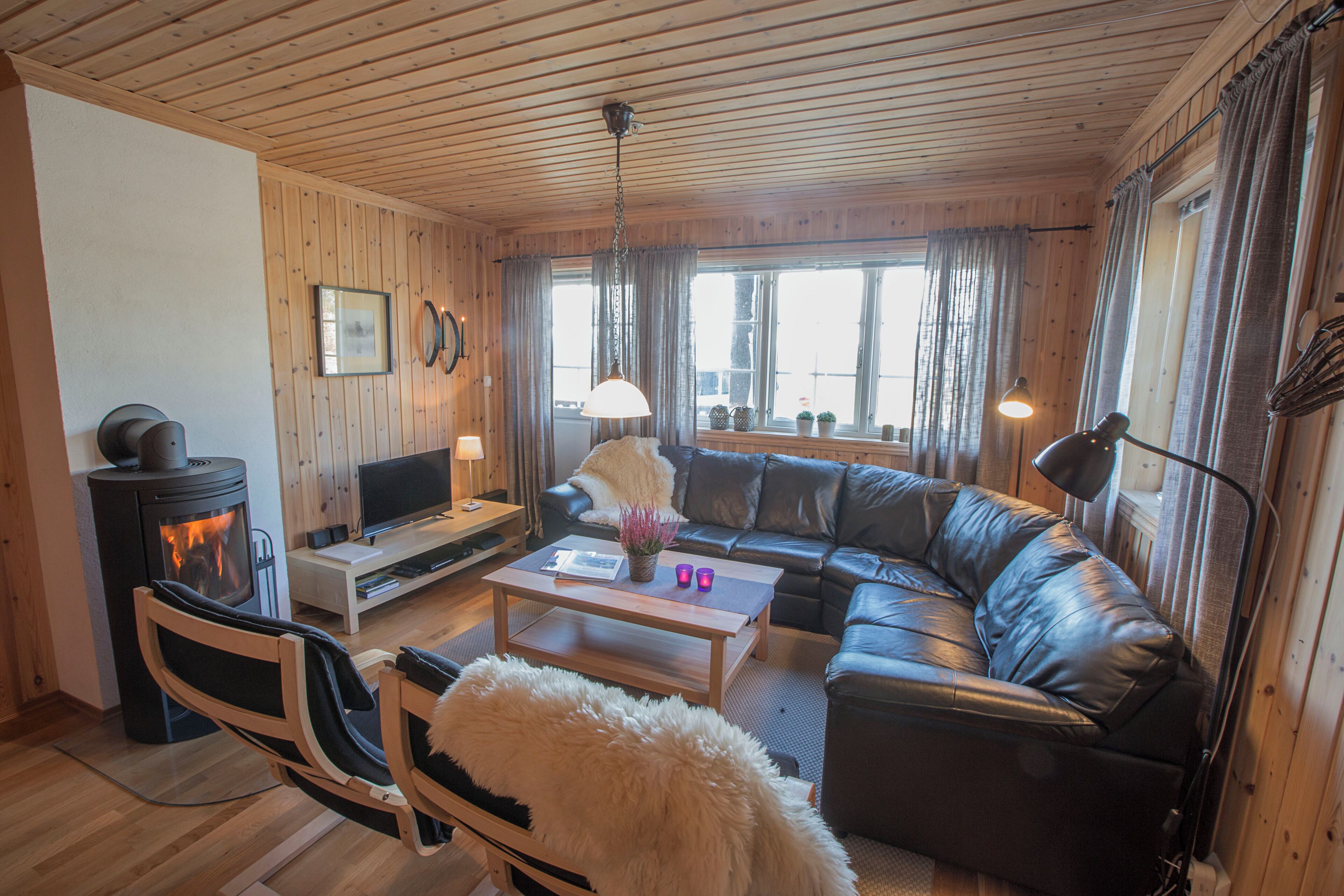 A cozy living room with a fireplace, leather sofa, and a television.