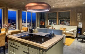 A modern kitchen with a central island, a built-in stove, and a large window overlooking a scenic view. - Rauland Feriesenter (Vinje)