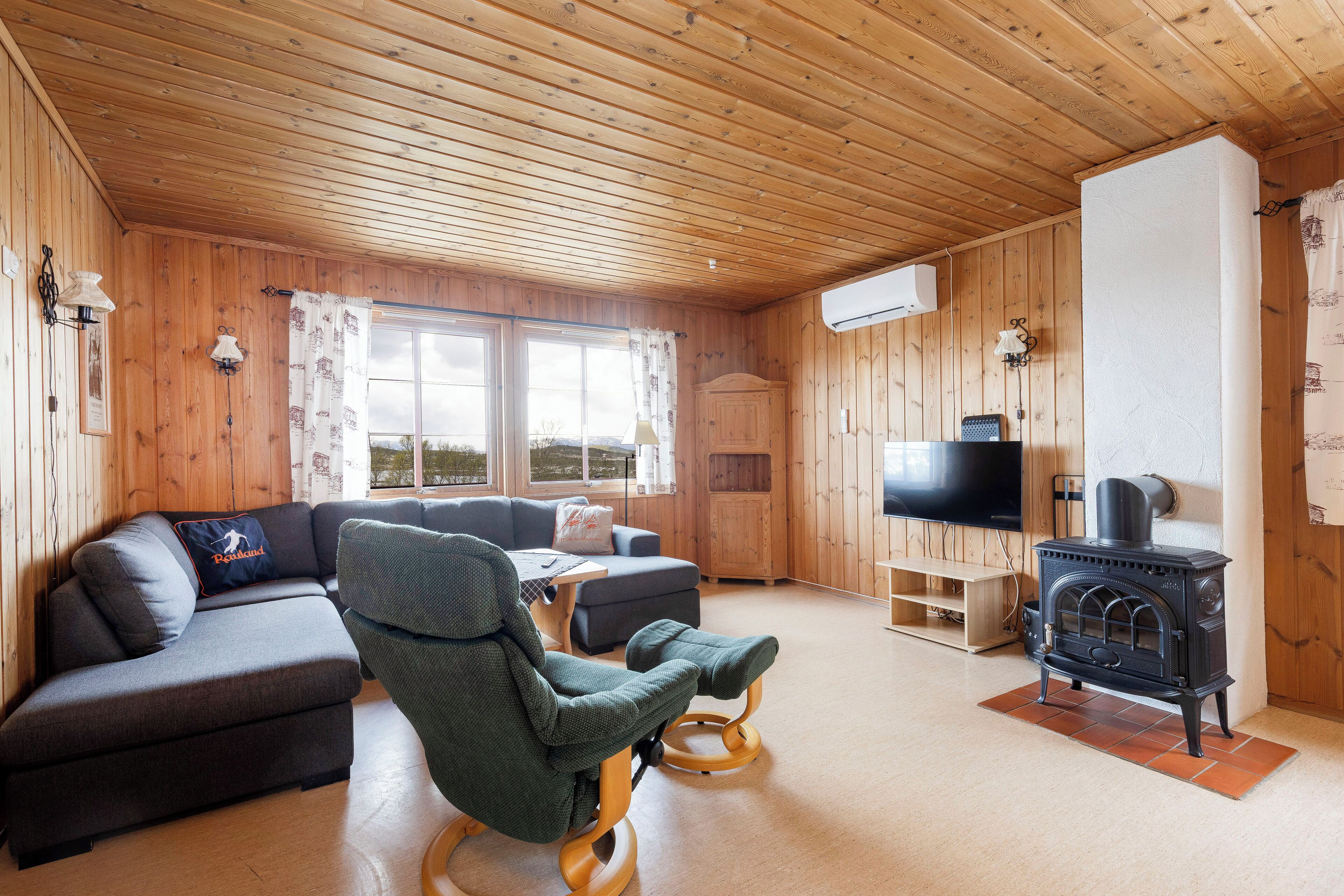 Una sala de estar acogedora con un sofá, un sillón mecedor, un televisor y una chimenea de leña.
