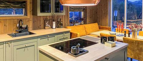 A modern kitchen with a central island, wooden cabinetry, and a large window.