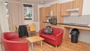 Une cuisine compacte avec des meubles en bois, un four encastré et une petite table à manger.