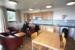 A modern kitchen with wooden cabinets, a dining table, and red chairs.