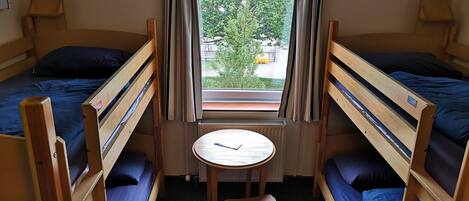 A room with two bunk beds, a small table, and a chair.