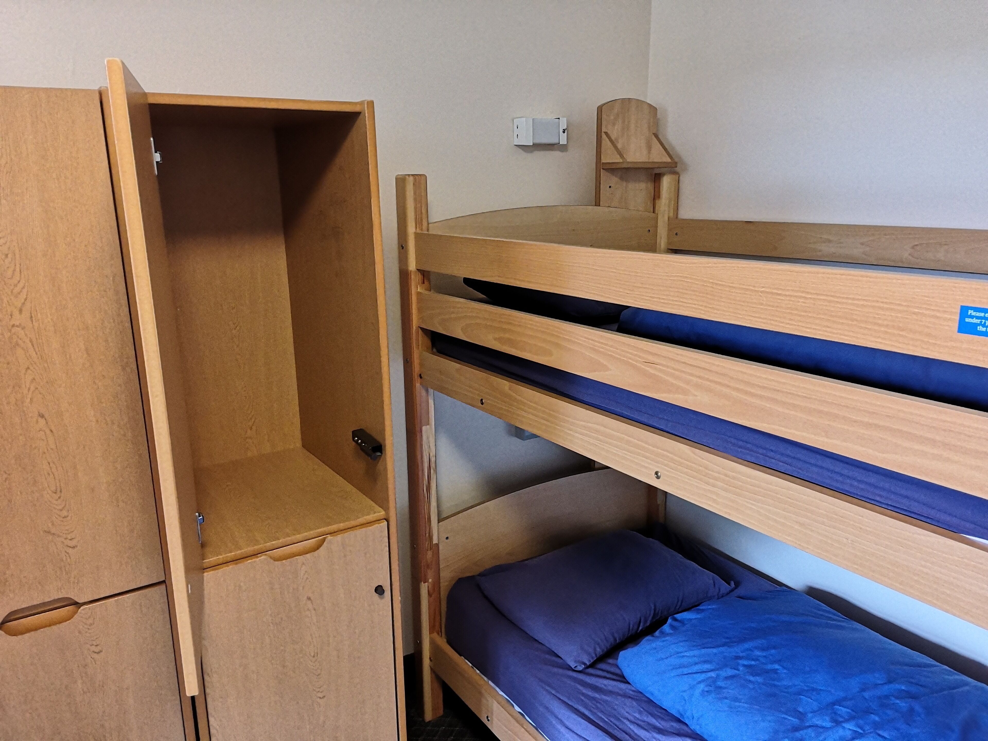 A bunk bed with a wooden wardrobe and a small desk.