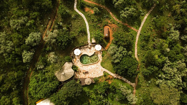 An aerial view of a resort with a swimming pool, stone pathways, and lush greenery. - Entumoto Safari Camp (Maasai Mara)