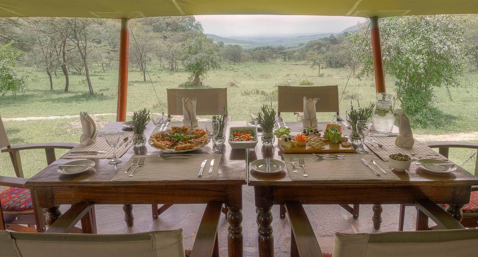 A dining table set for two with a scenic view, surrounded by chairs, and a bench.