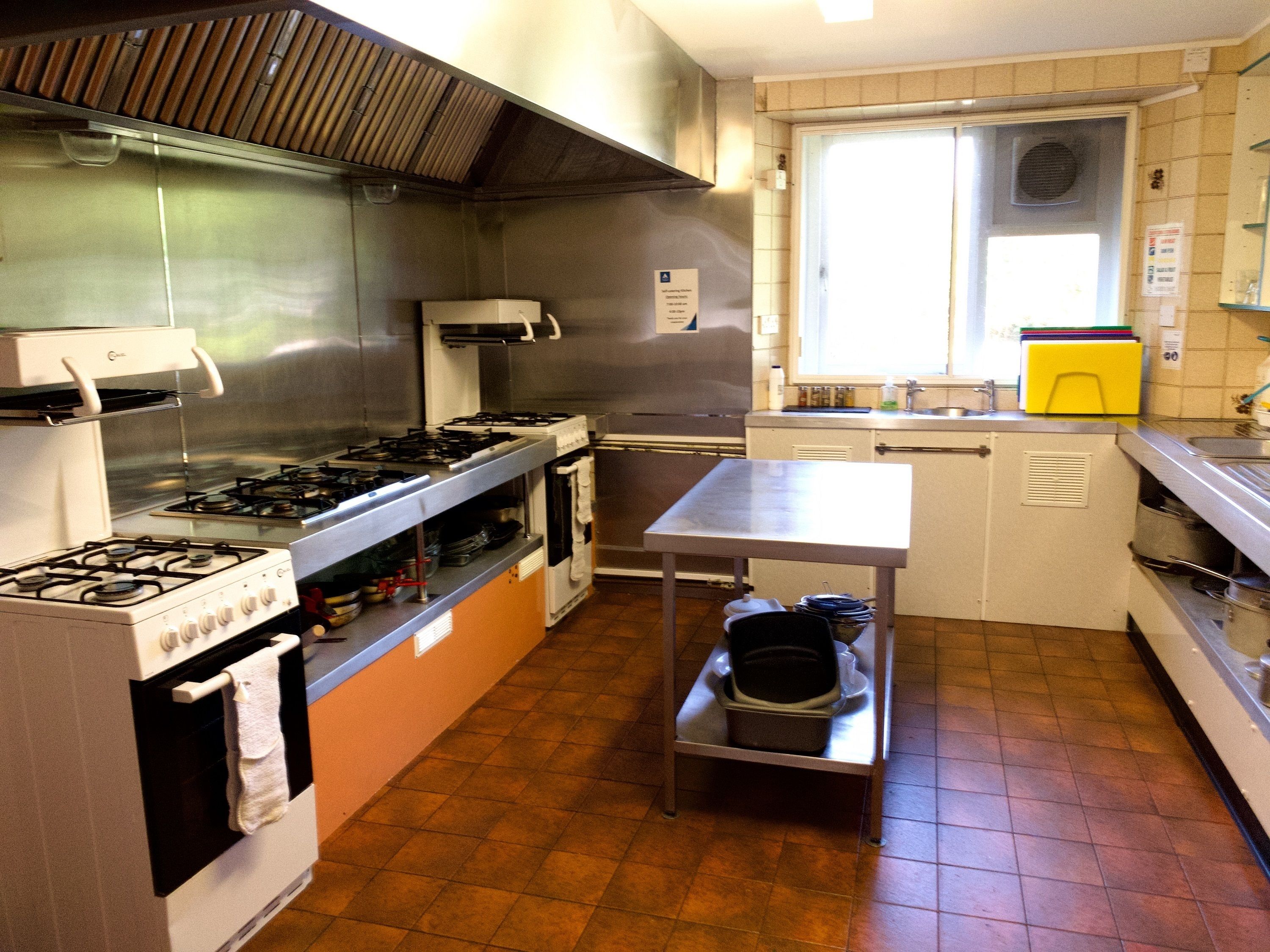 A kitchen with stainless steel appliances, a window, and a tiled floor.