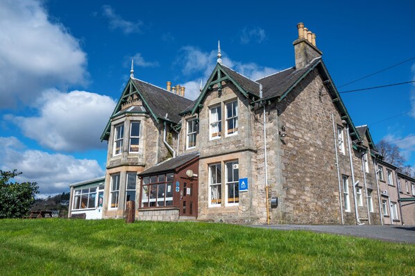 A stone building with a traditional architectural style, featuring multiple windows and a prominent entrance.
