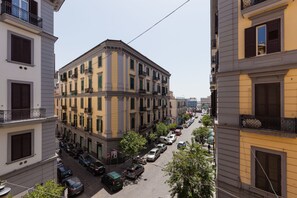 A multi-story building with a corner entrance, parked cars along the street, and a clear sky. - Residenza Duomo 314 (Naples)
