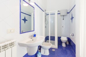 A bathroom with a white sink, a bidet, a toilet, and a glass-enclosed shower. - Residenza Duomo 314 (Naples)