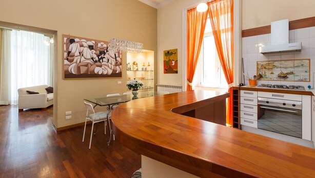 A modern kitchen with a wooden countertop, a built-in oven, and a dining area with a glass table and chairs. - Residenza Duomo 314 (Naples)