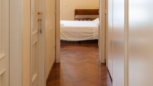 A narrow hallway with wooden flooring leading to a bedroom with a bed. - Residenza Duomo 314 (Naples)