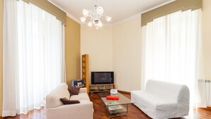 A living room with a sofa, a coffee table, a television, and a wooden floor. - Residenza Duomo 314 (Naples)